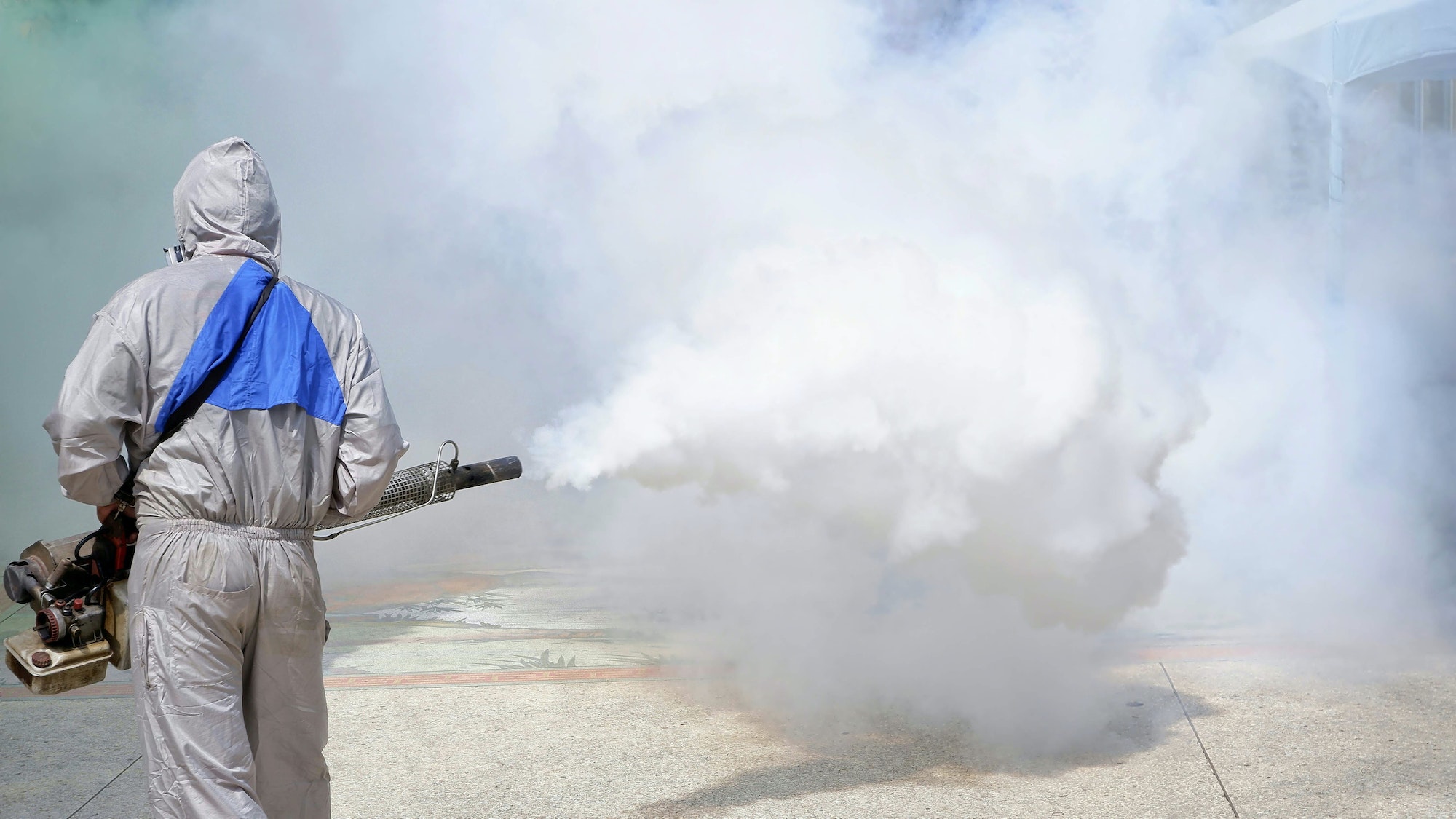 Healthcare worker spraying chemical to eliminate mosquitoes and prevent dengue fever in public area