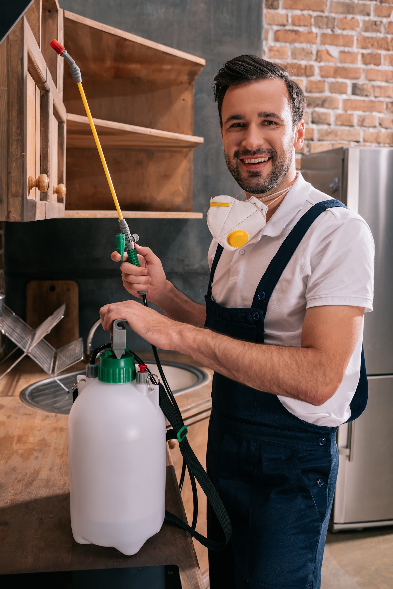 smiling pest control worker holding sprayer in kitchen